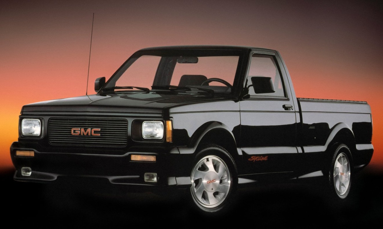 GMC Syclone preta parada de frente com fundo em laranja
