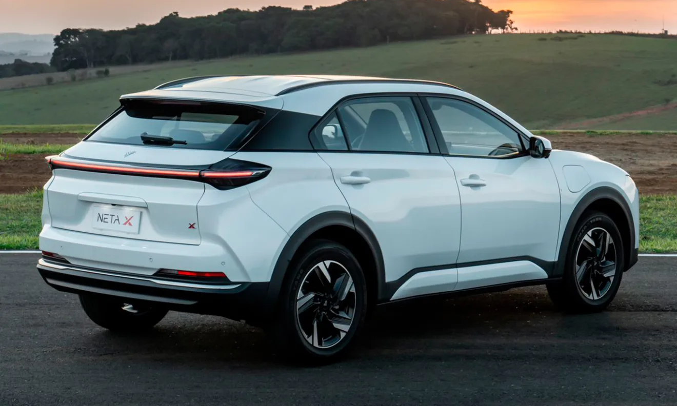 Neta X branco parado de traseira com árvores ao fundo