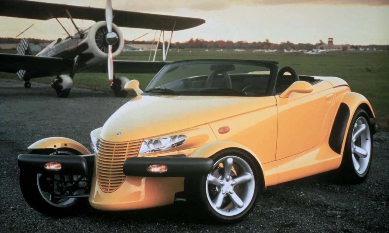 Plymouth Prowler amarelo parado de frente com avião ao fundo