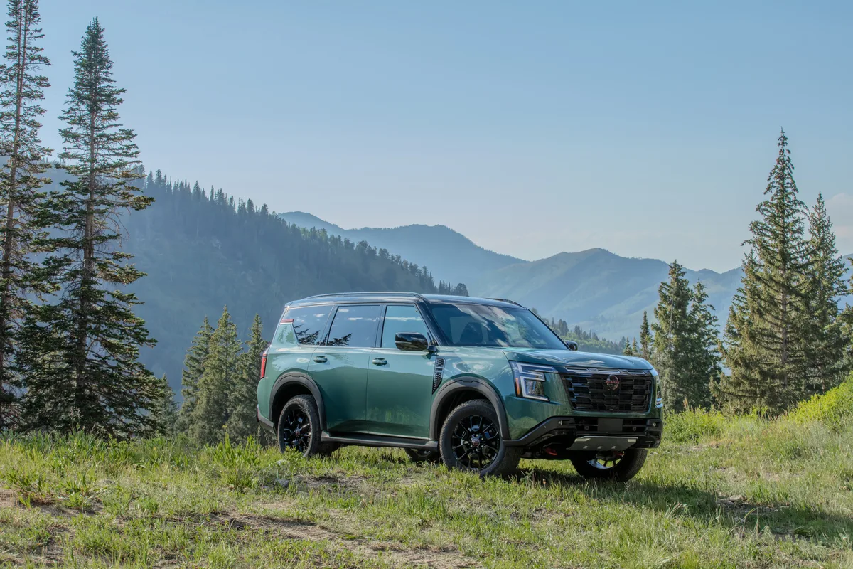 Nissan Armada Pro-4X verde parado na grama com montanhas ao fundo