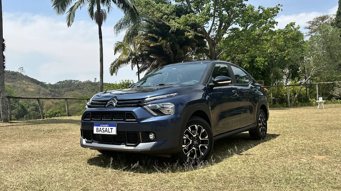 Citroën Basalt Shine Turbo 200 azul parado em meio a um gramado com uma floresta ao fundo