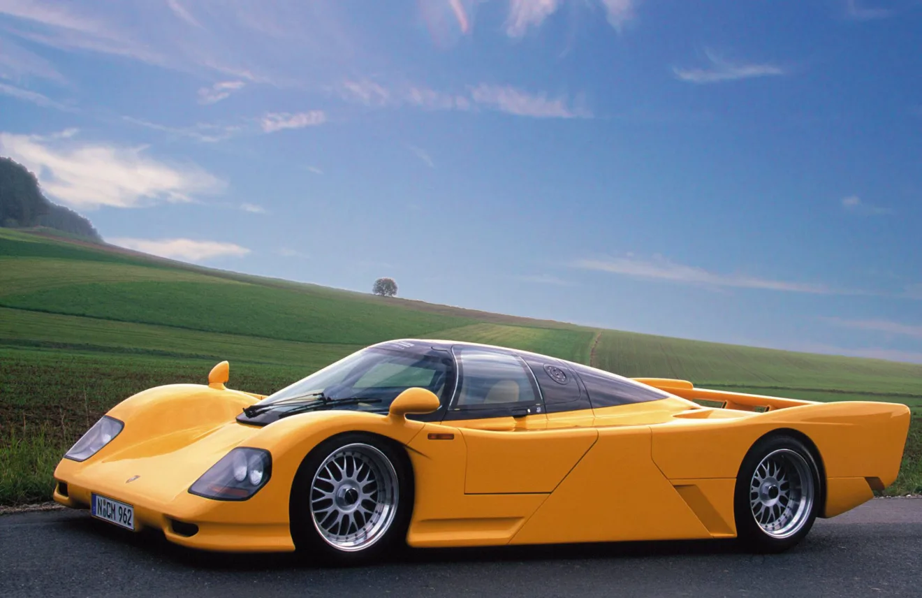 Dauer 962 amarelo de lado com paisagem ao fundo