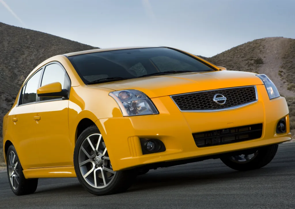 Nissan Sentra SE-R Spec V amarelo de frente no asfalto com montanhas ao fundo