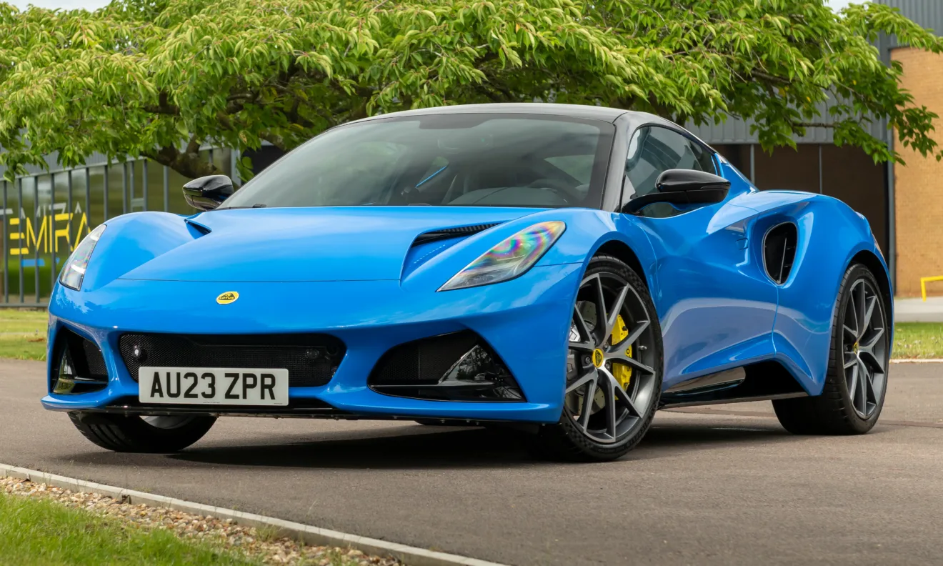 Lotus Emira First Edition azul claro, visto de frente e com árvore atrás