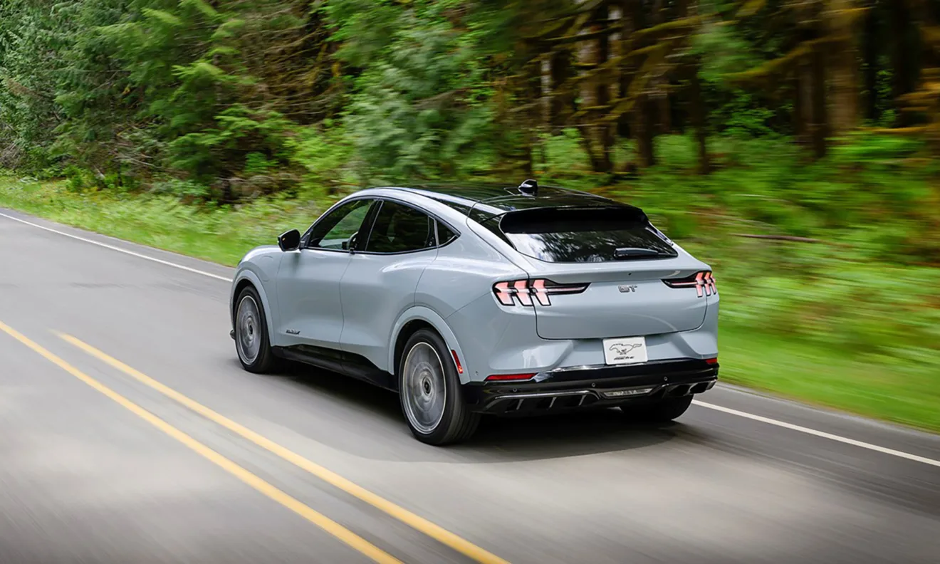 Ford Mustang Mach-E 2024 cinza de traseira andando na estrada é um modelo elétrico à venda em nosso mercado 