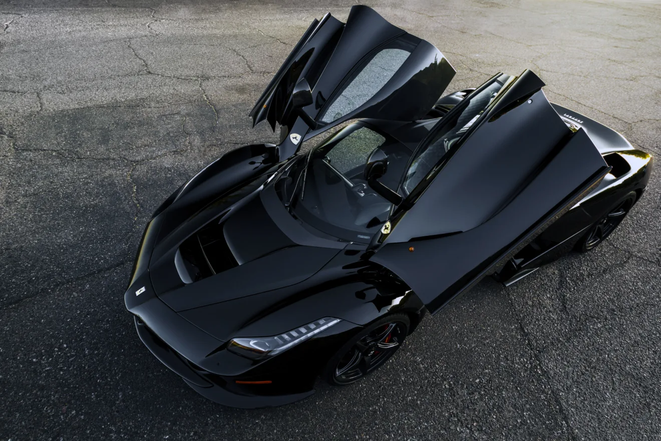 Ferrari LaFerrari preta, com portas abertas, visto de cima e com rua ao fundo
