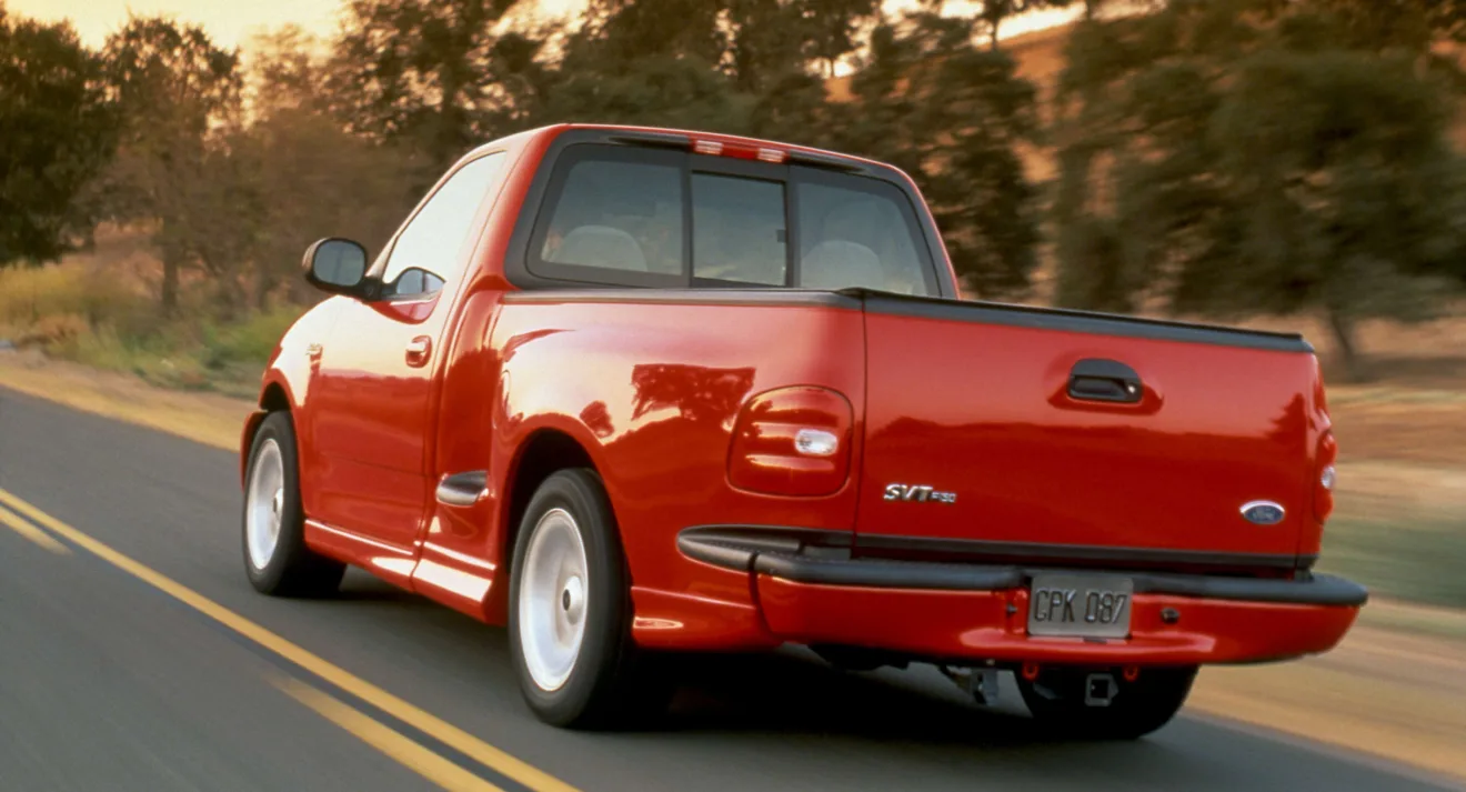 Ford F-150 Lightning vermelha de traseira andando na estrada