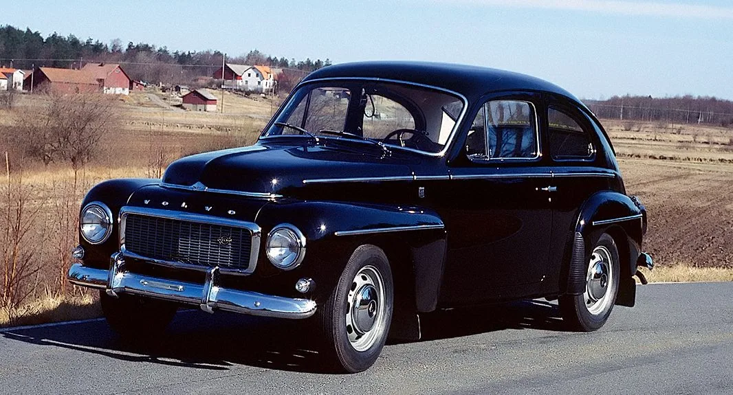 Volvo PV544 F preto parado na estrada com casas ao fundo