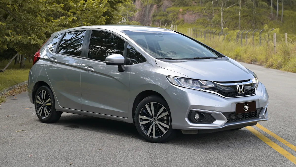 Honda Fit prata de frente em um fundo florestal