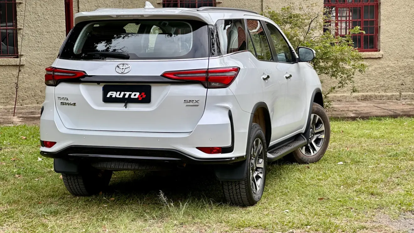 Toyota SW4 SRX Platinum 7 lugares branco de traseira com uma casa antiga e um gramado ao fundo