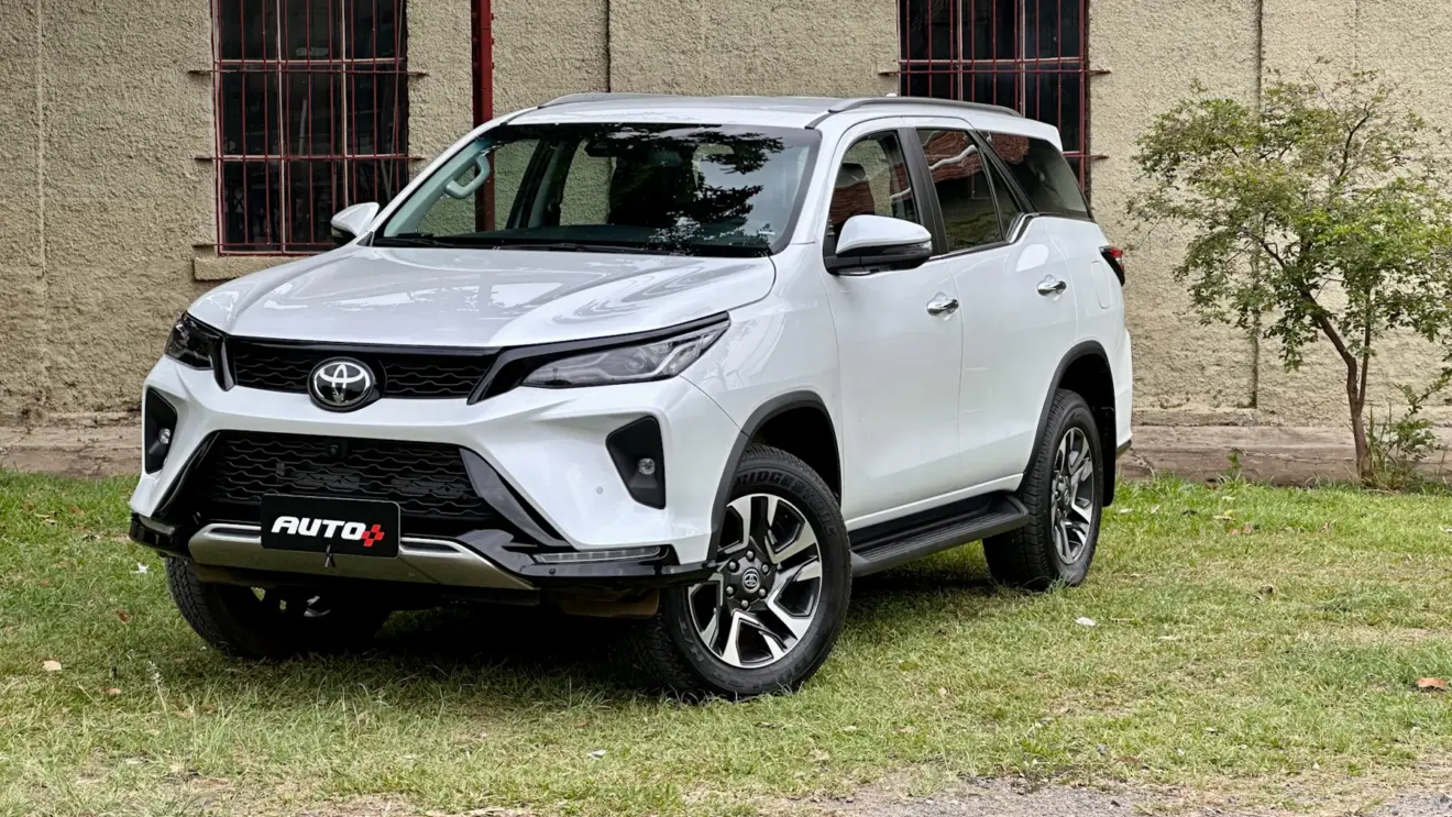 Toyota SW4 SRX Platinum 7 lugares branco de frente com uma casa antiga e um gramado ao fundo