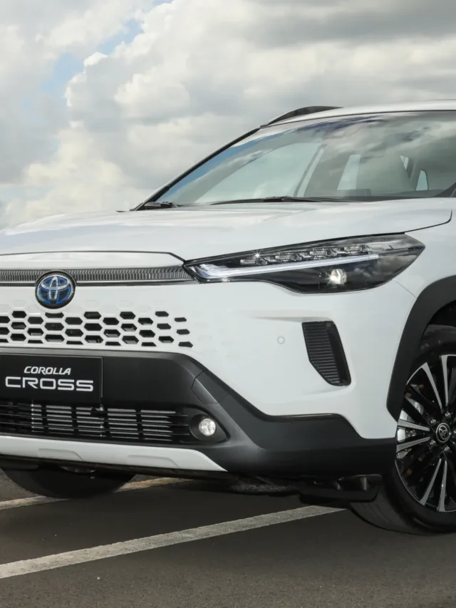 Toyota Corolla Cross 2026 branco visto lateralmente, com faróis, DRL's e iluminadores de neblina acesos - Veja preços - Carro elétrico polui mais que híbrido