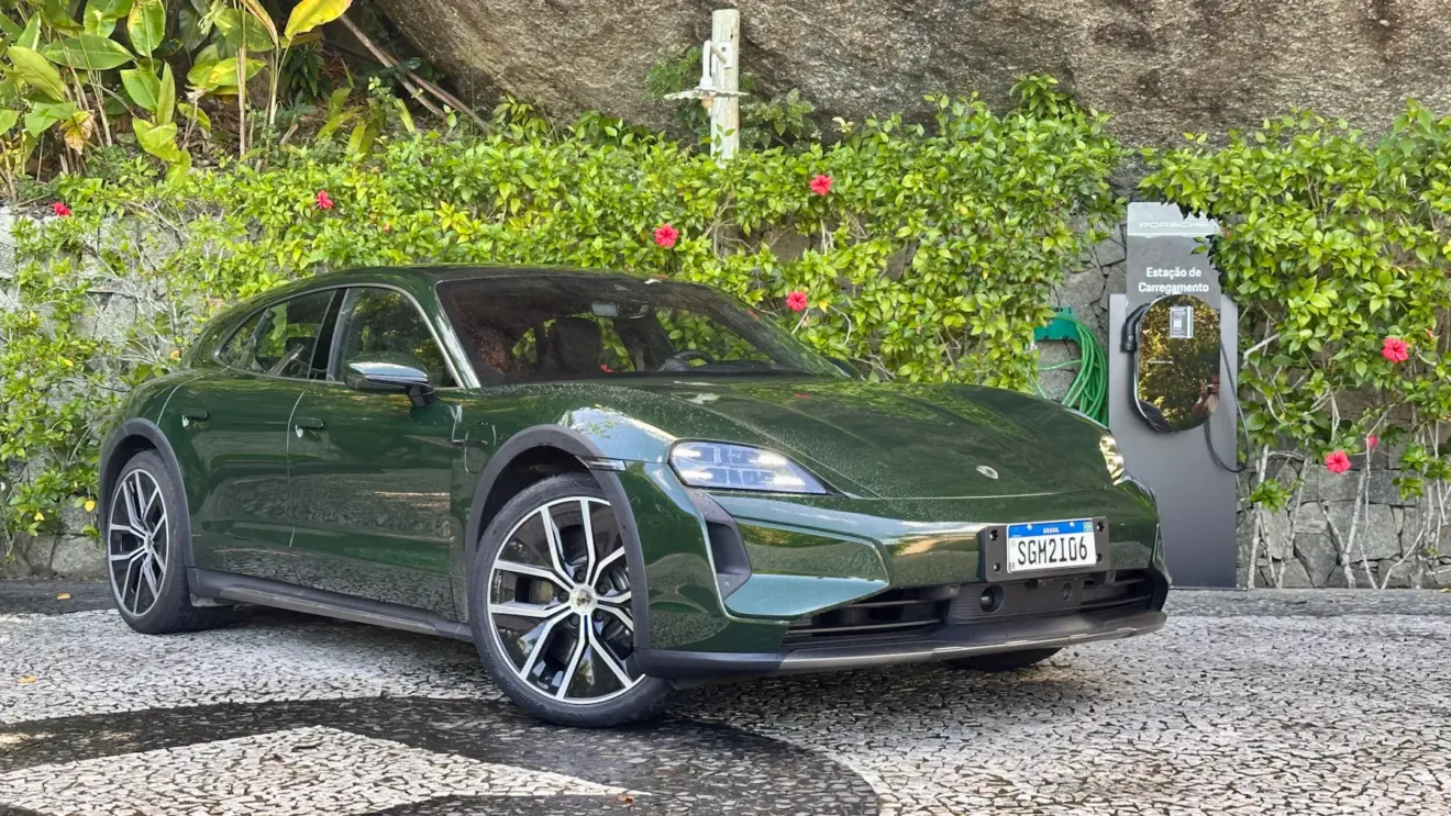 Porsche Taycan Cross Turismo Turbo verde de frente em um jardim com um carregador da Porsche ao lado