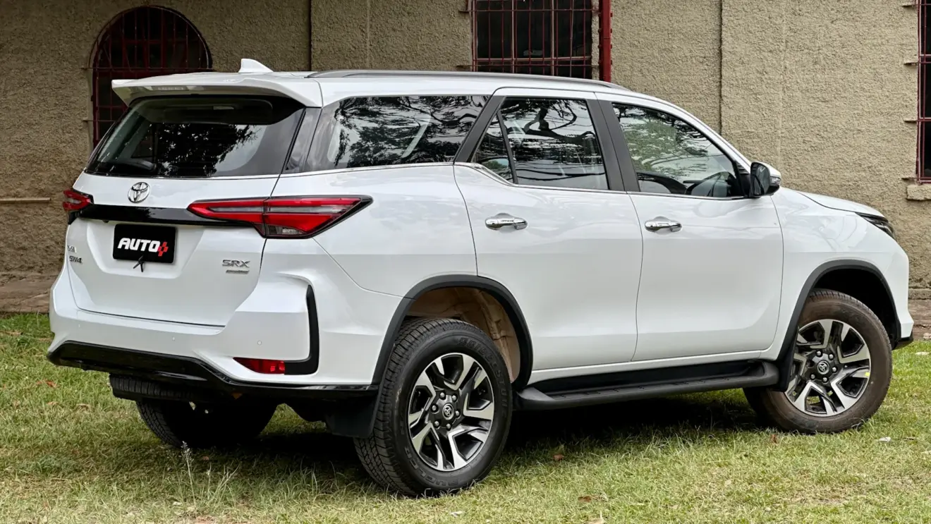 Toyota SW4 SRX Platinum 7 lugares branco de traseira com uma casa antiga e um gramado ao fundo