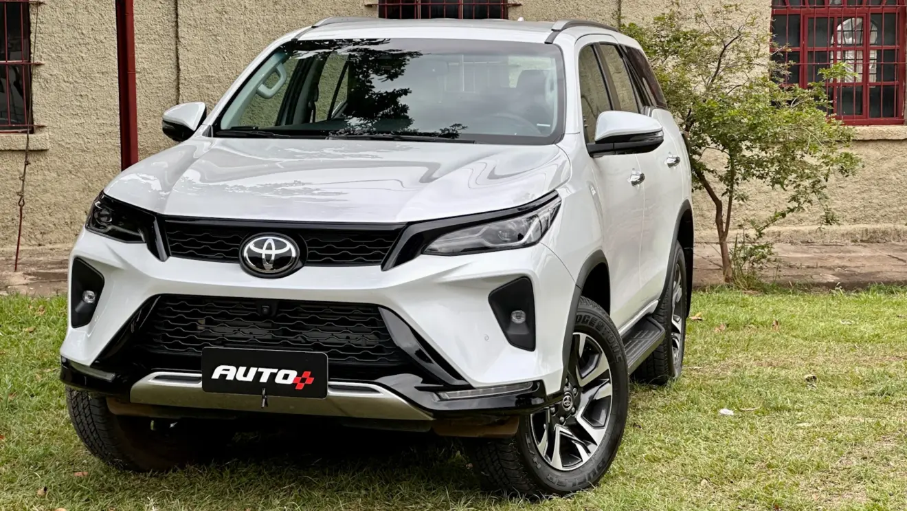 Toyota SW4 SRX Platinum 7 lugares branco de frente com uma casa antiga e um gramado ao fundo