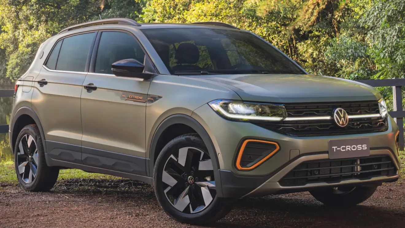 Volkswagen T-Cross 2026 Extreme cinza esverdeado, com detalhes pretos e laranja. visto de frente e com faróis acesos