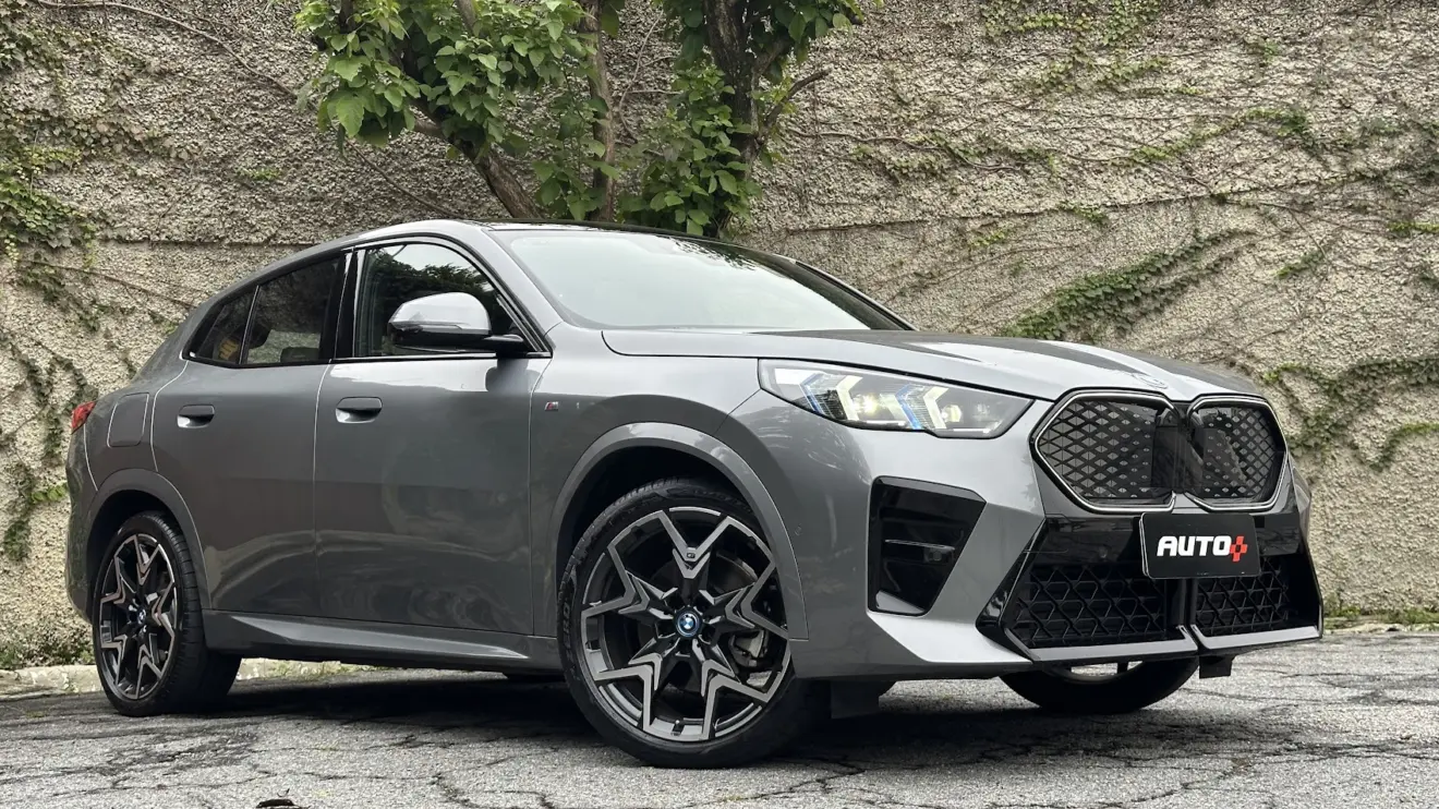 BMW iX2 cinza parado de frente com muro de cimento ao fundo