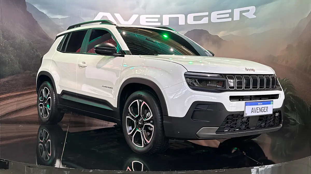 Jeep Avenger branco em uma plataforma com o nome AVENGER no fundo