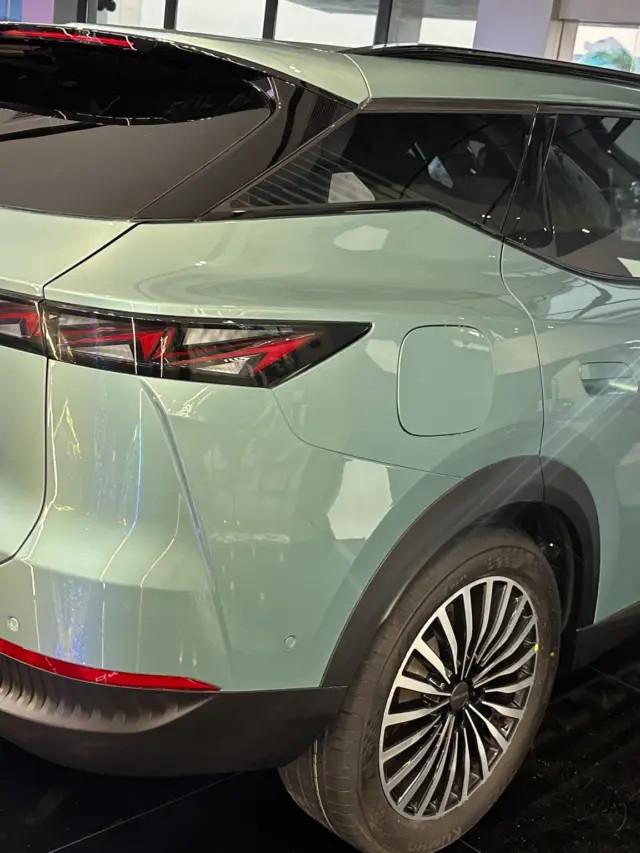 Omoda 7 híbrido plug-in azul visto de trás e estacionado em um estande preto