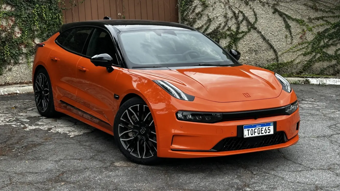 Zeekr 001 laranja parado de frente com muro de cimento ao fundo