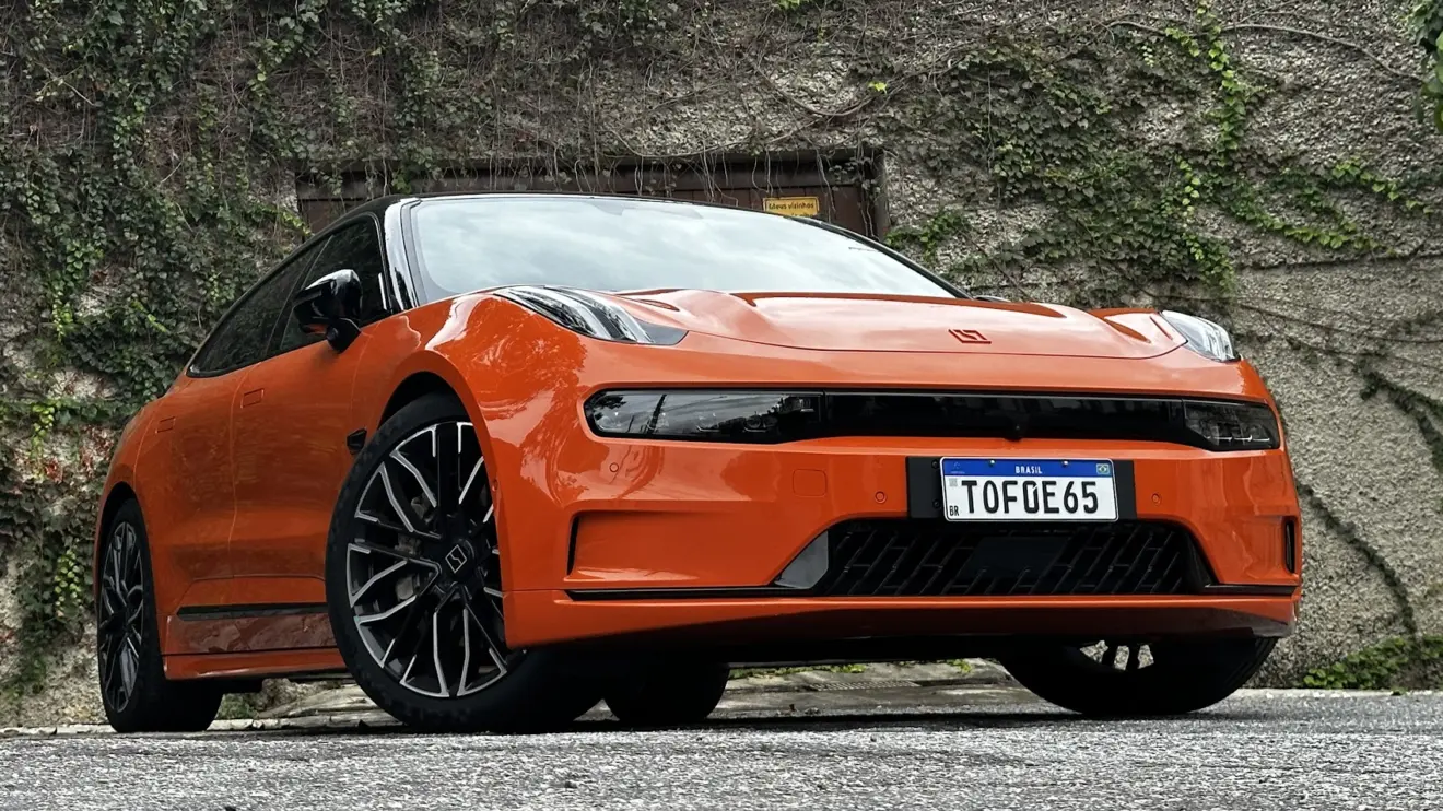 Zeekr 001 laranja parado de frente com muro e plantas ao fundo