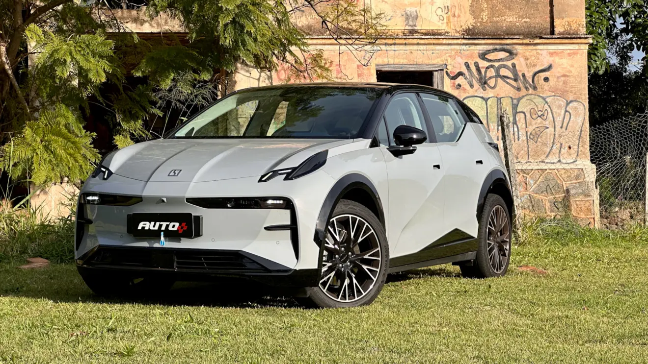 Zeekr X Flagship cinza com teto preto em frente a uma casa abandonada