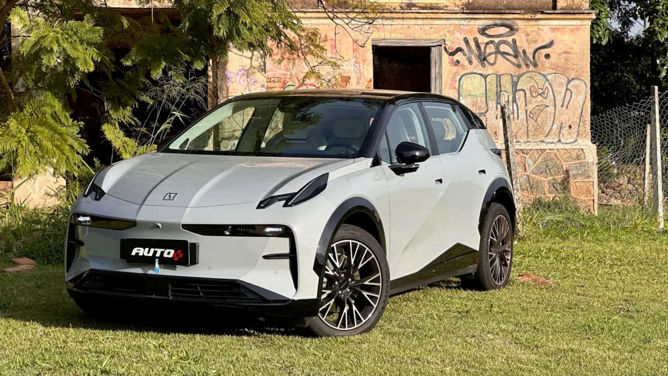 Zeekr X Flagship cinza de frente em um gramado com uma casa abandonada ao fundo