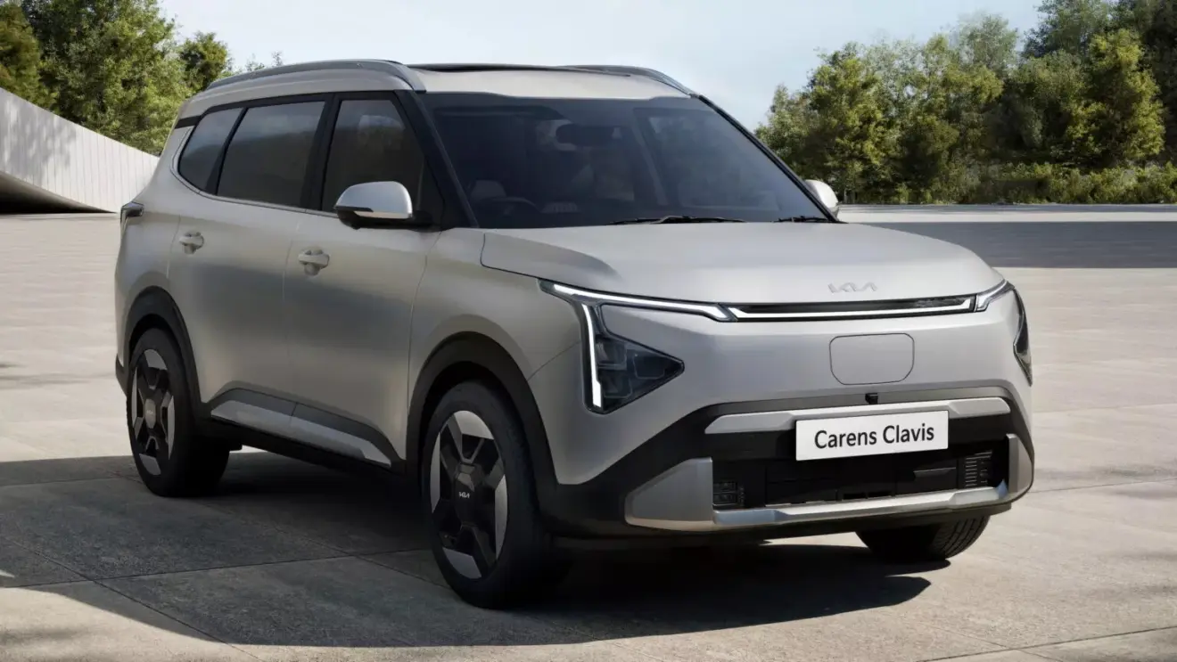 Kia Carens Clavis EV prata, vista de frente e com DRL's acesos