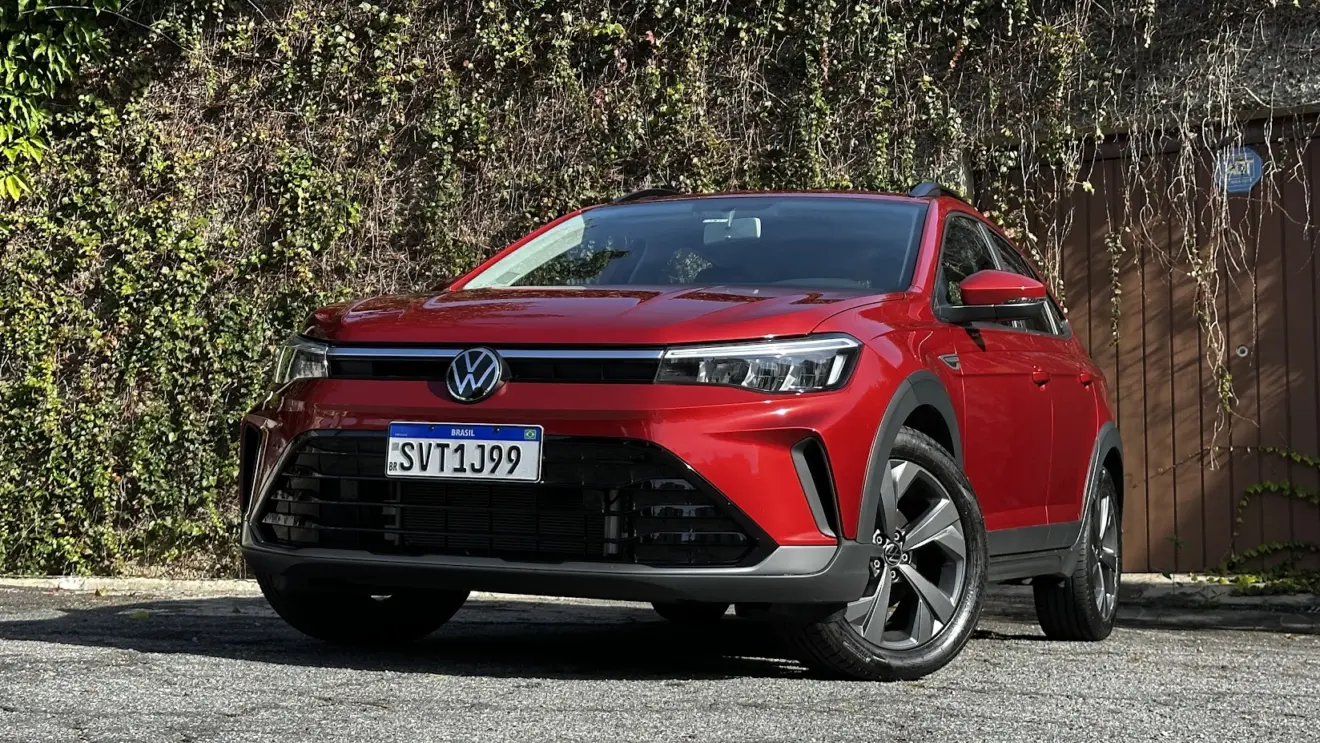 Volkswagen Nivus Comfortline 200TSI vermelho parado de frente com muro e plantas ao fundo