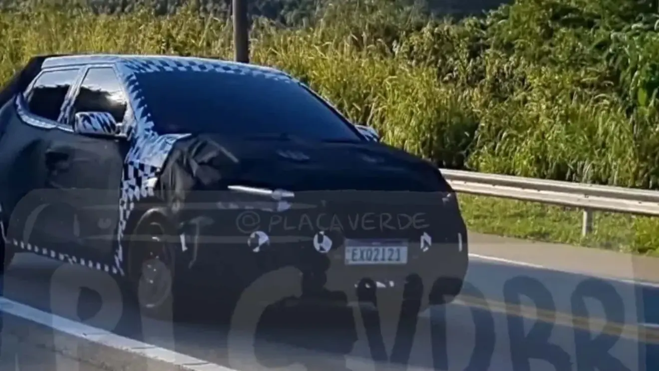 Protótipo camuflado de preto do novo Hyundai HB20 visto de frente e com DRL's acesos