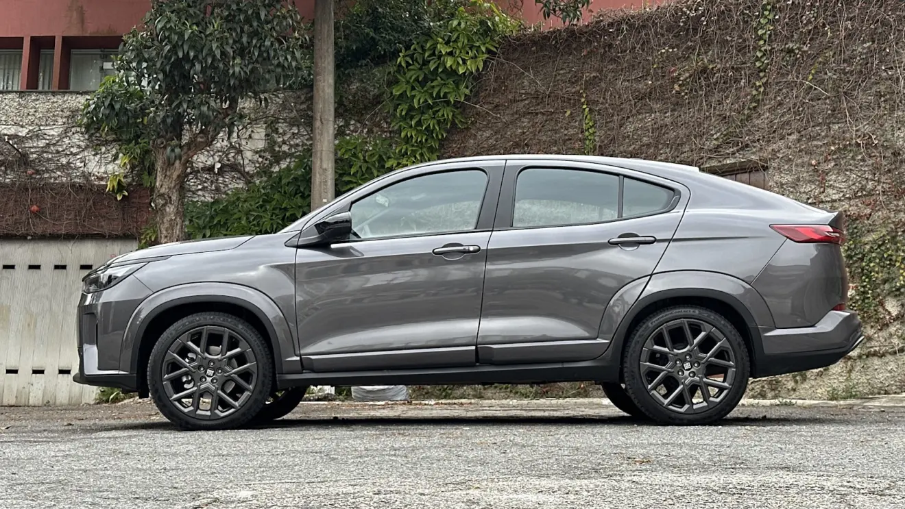 Fiat Fastback Impetus Hybrid cinza parado de lateral com muro ao fundo