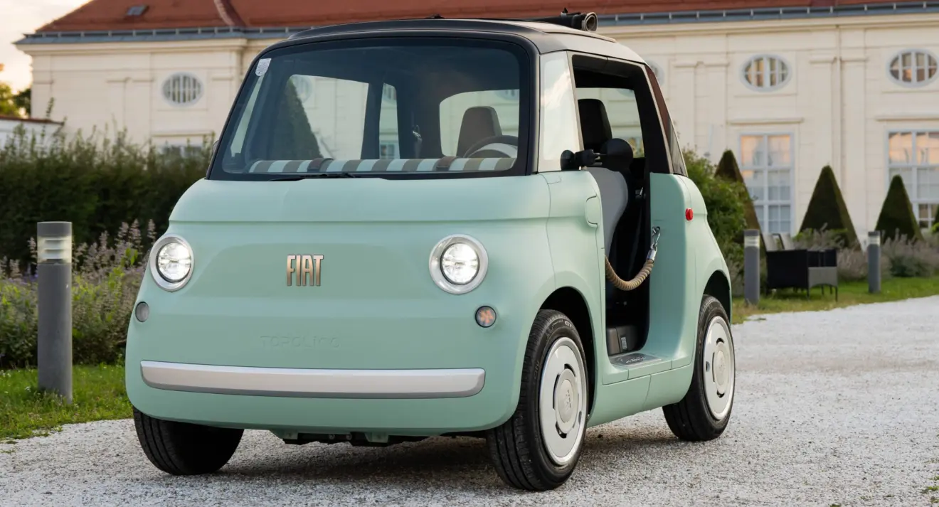 Fiat Topolino verde parado de frente com casa ao fundo