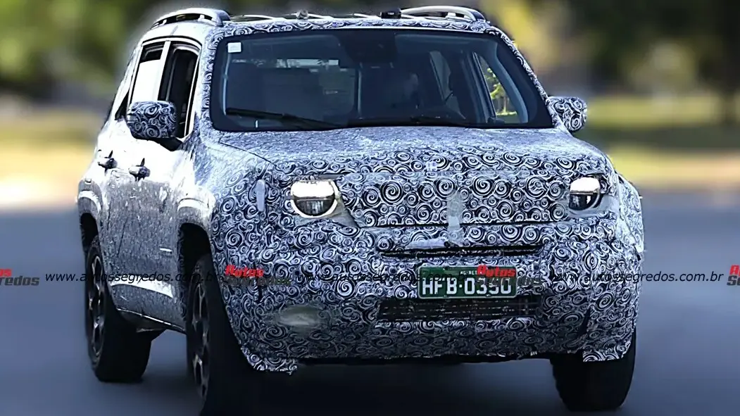 Protótipo do Jeep Renegade camuflado, visto de frente e com faróis acesos