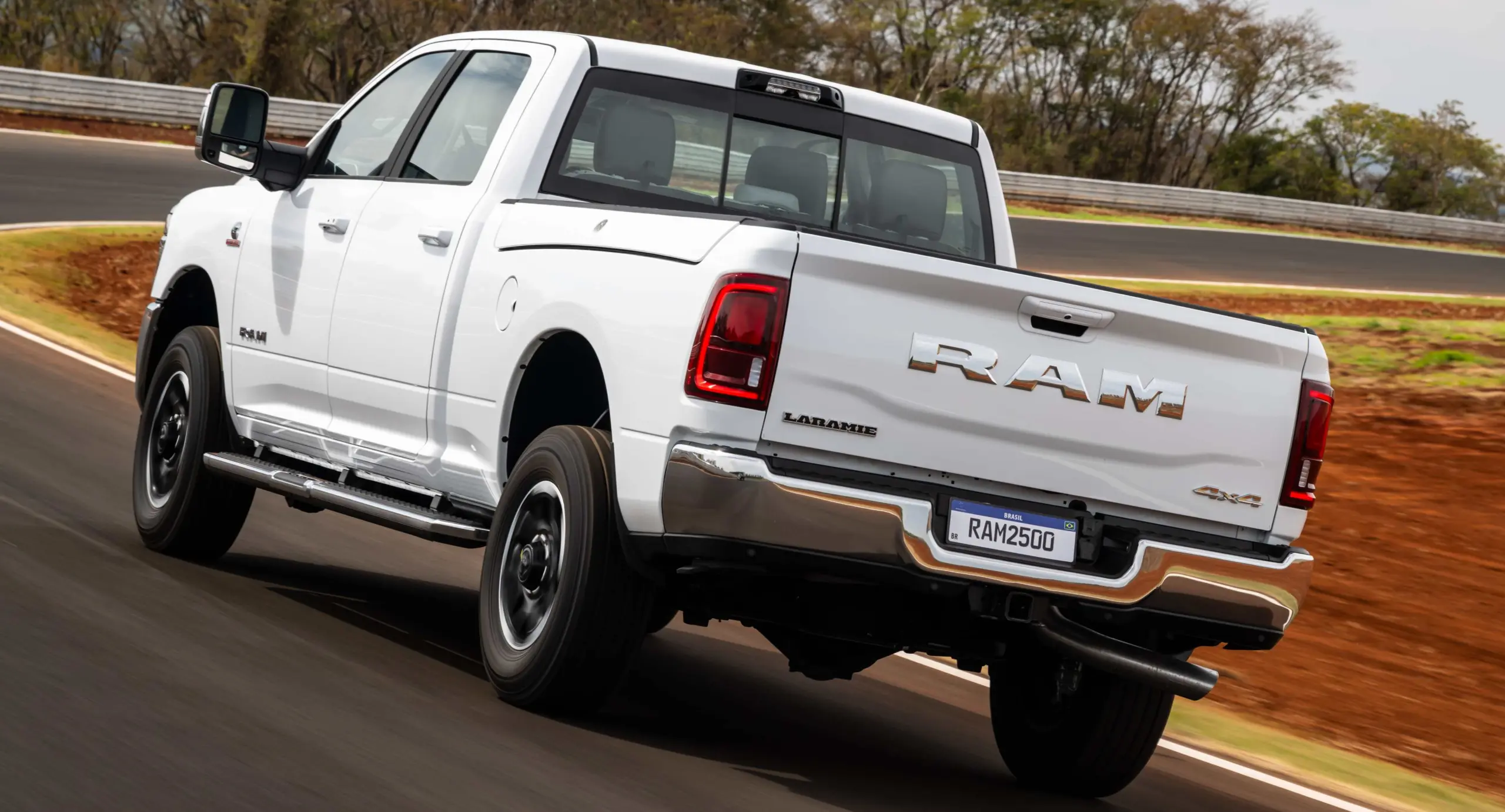 Ram 2500 Laramie branca de traseira andando na pista