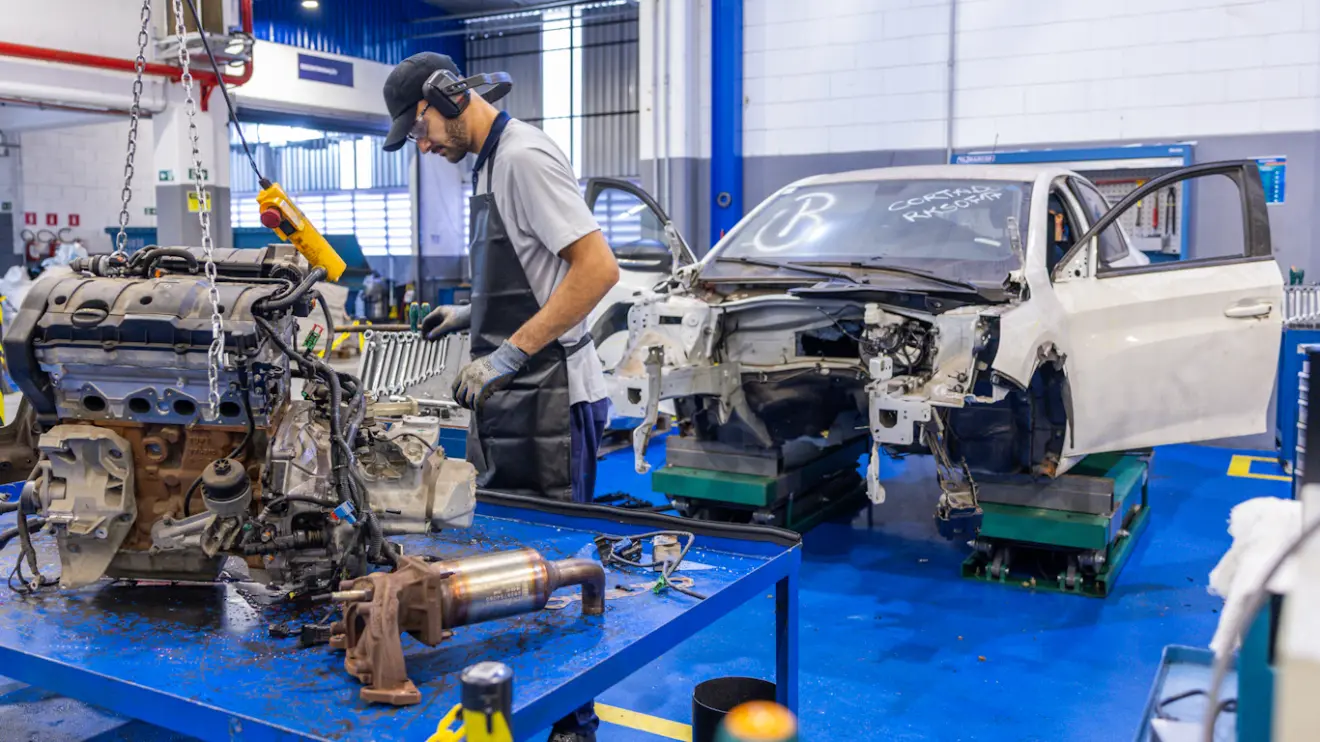 funcionário e carcaça de carro desmontado em centro de desmontagem da Stellantis