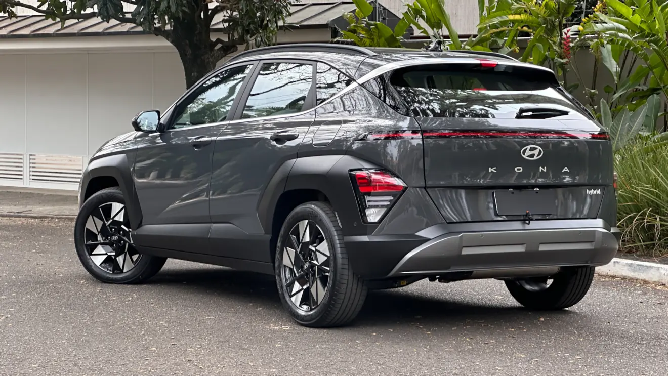 Hyundai Kona cinza parado de traseira com casa ao fundo