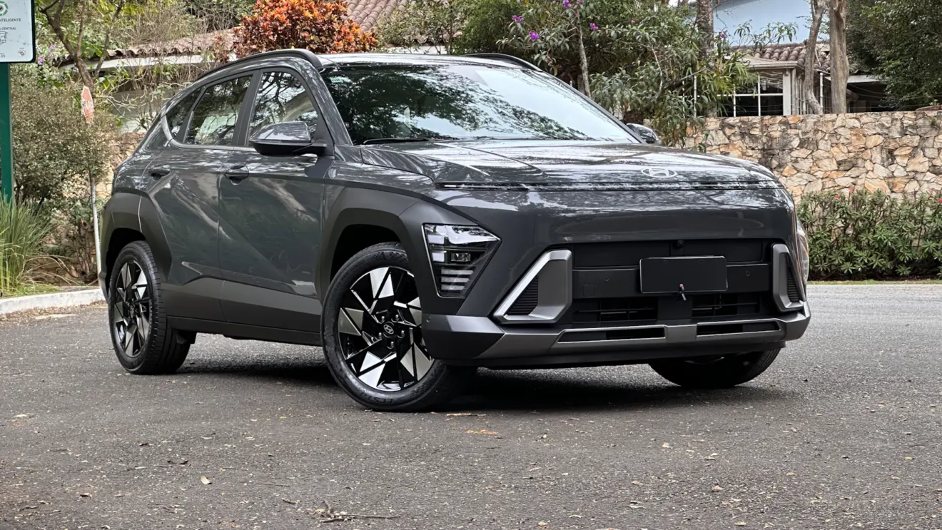 Hyundai Kona cinza parado de frente no asfalto com muro ao fundo