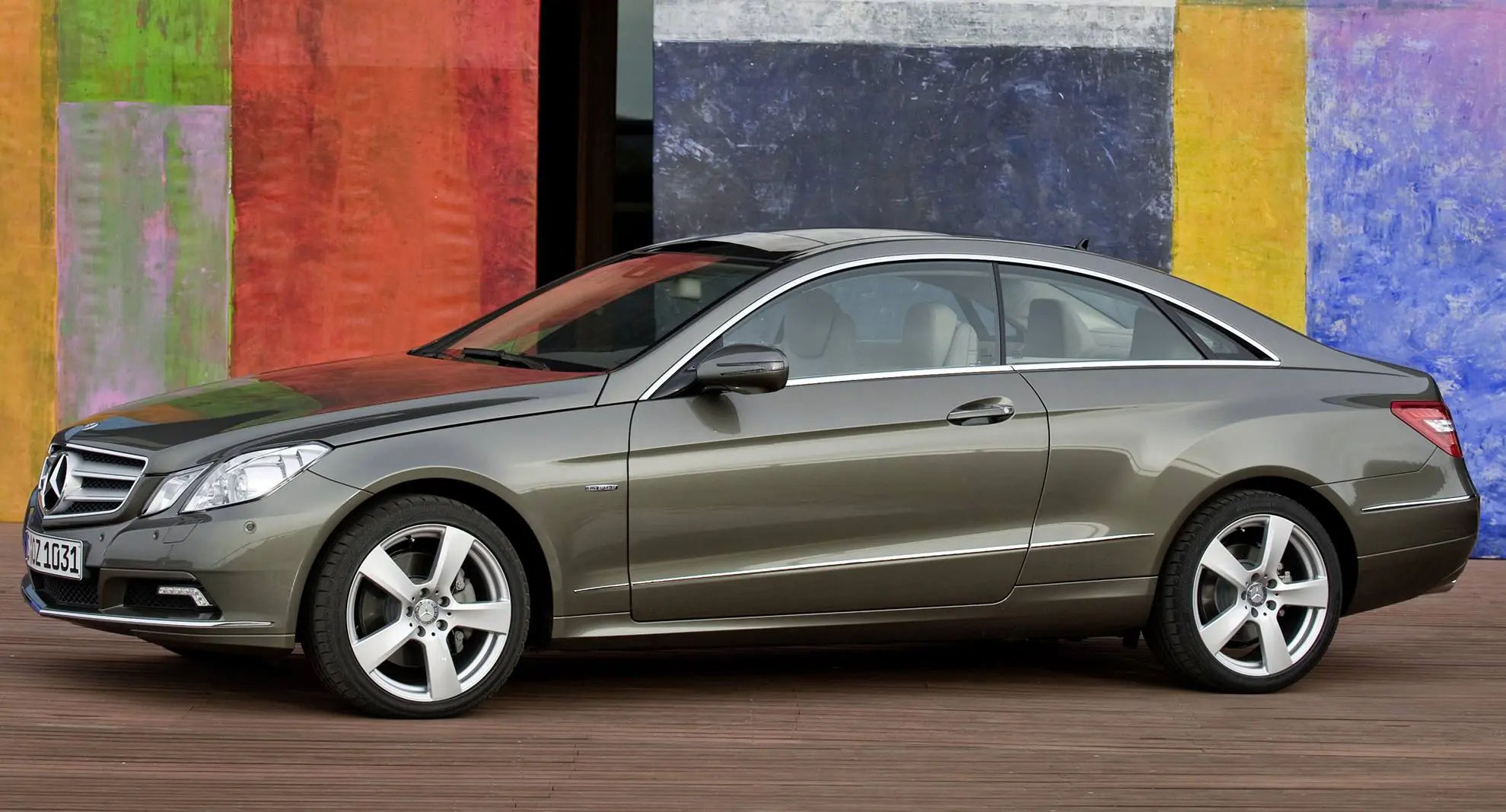 Mercedes-Benz E 350 verde parada de lateral com muro colorido