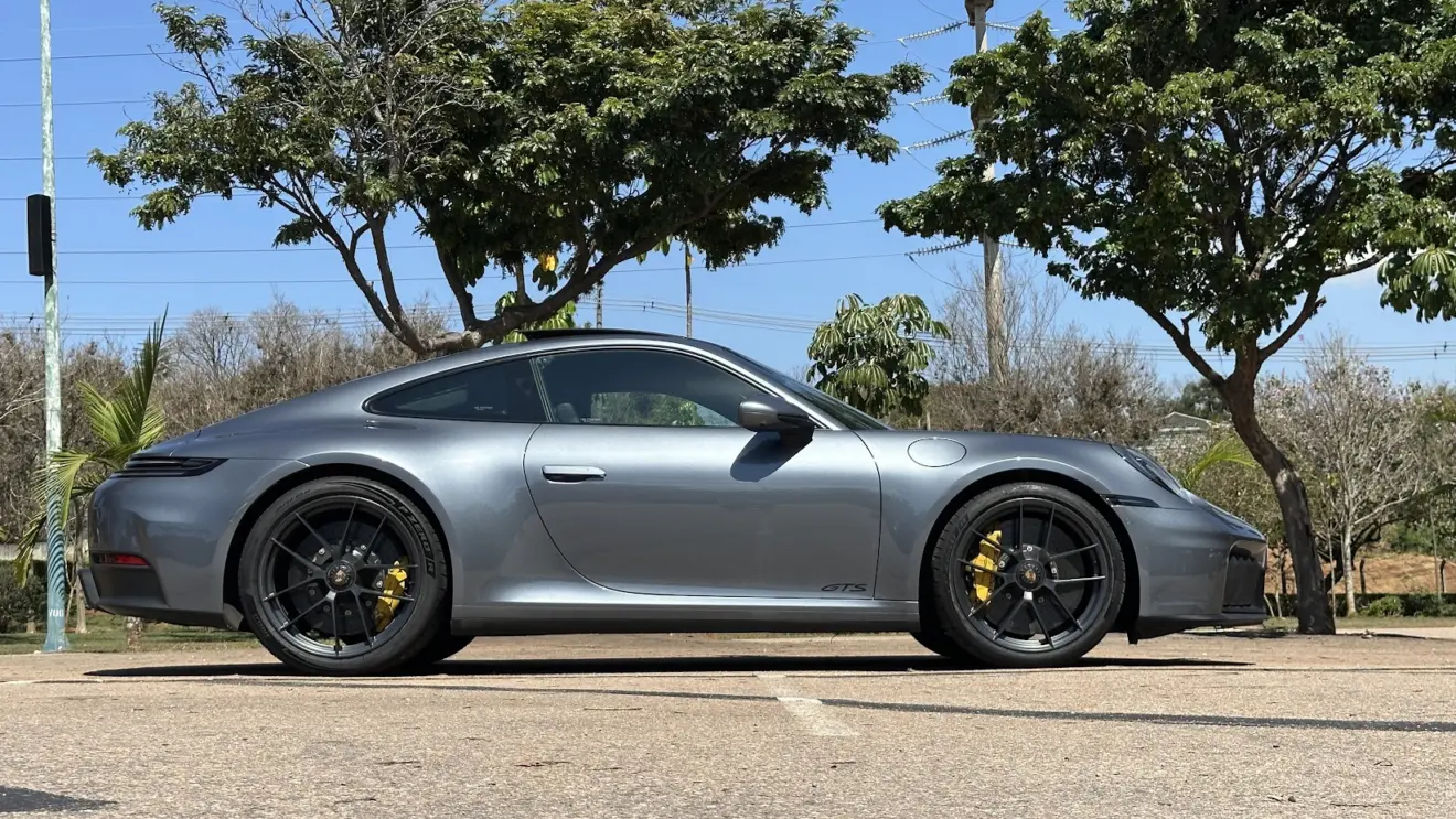 Porsche 911 Carrera GTS cinza parado de traseira com árvores ao fundo