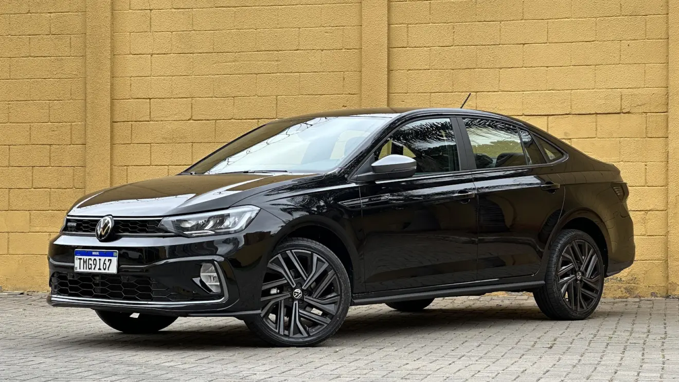 Volkswagen Virtus Exclusive 250 TSI preto parado de frente com muro amarelo ao fundo