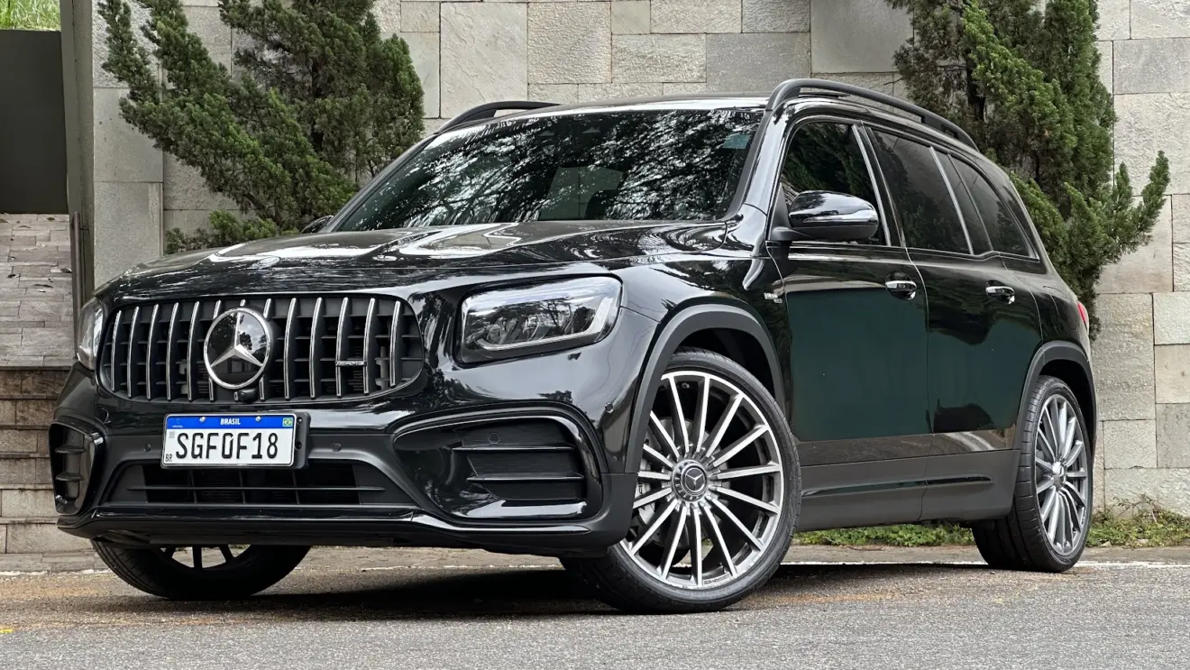 Mercedes-AMG GLB 35 4Matic preto parado de frente com muro de pedras e árvores ao fundo
