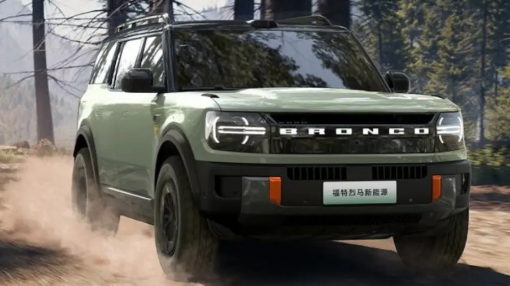 Ford Bronco elétrico cinza visto de frente e com faróis iluminados