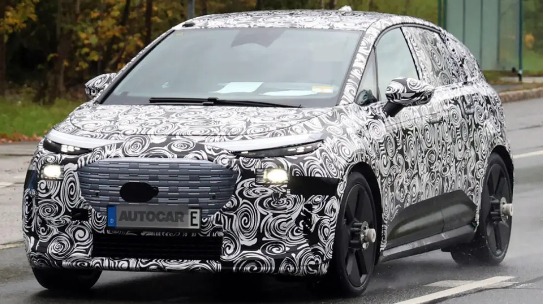 protótipo de novo SUV elétrico da Audi visto de frente, camuflado de preto e branco e com faróis acesos