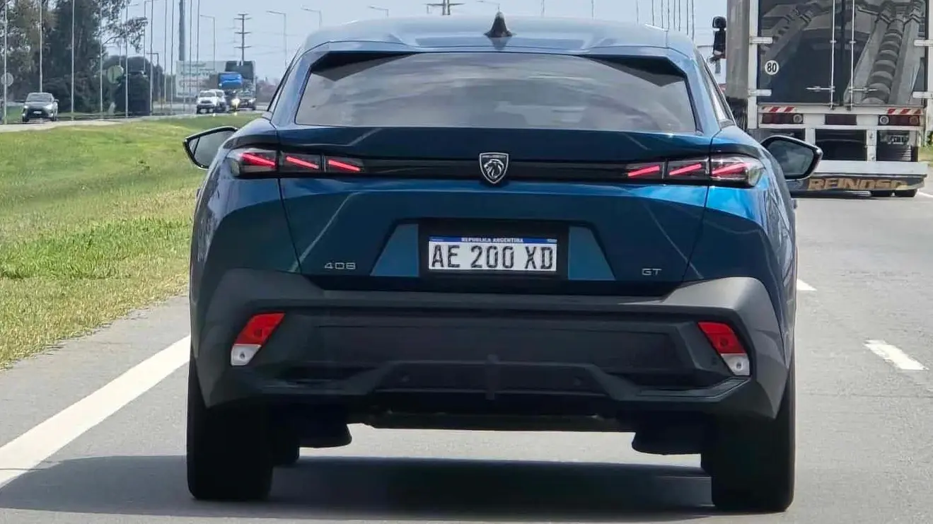 Peugeot 408 GT verde visto de trás e com lanternas acesas