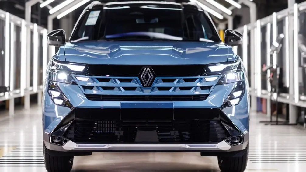 Renault Boreal azul com detalhes pretos visto de frente e com faróis acesos