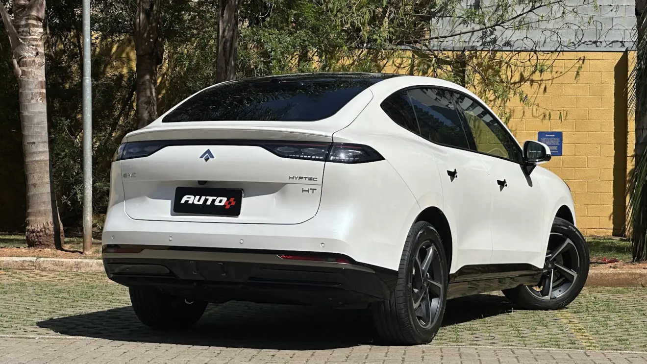 GAC Hyptec HT Elite branco parado de traseira com muro amarelo e plantas ao fundo