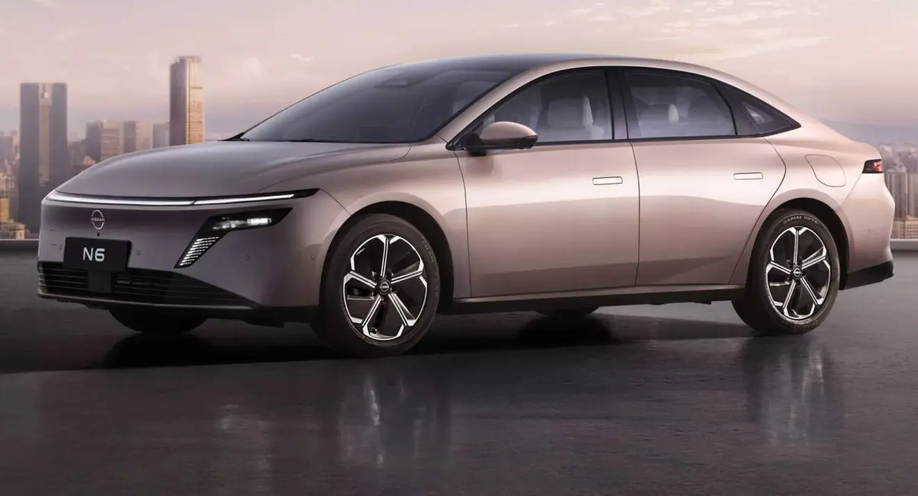 Nissan N6 dourado parado de dianteira com cidade ao fundo