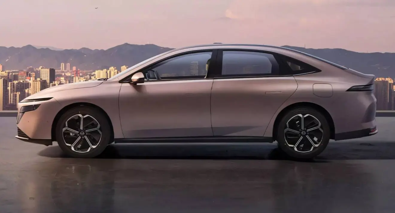 Nissan N6 dourado parado de lateral com cidade ao fundo