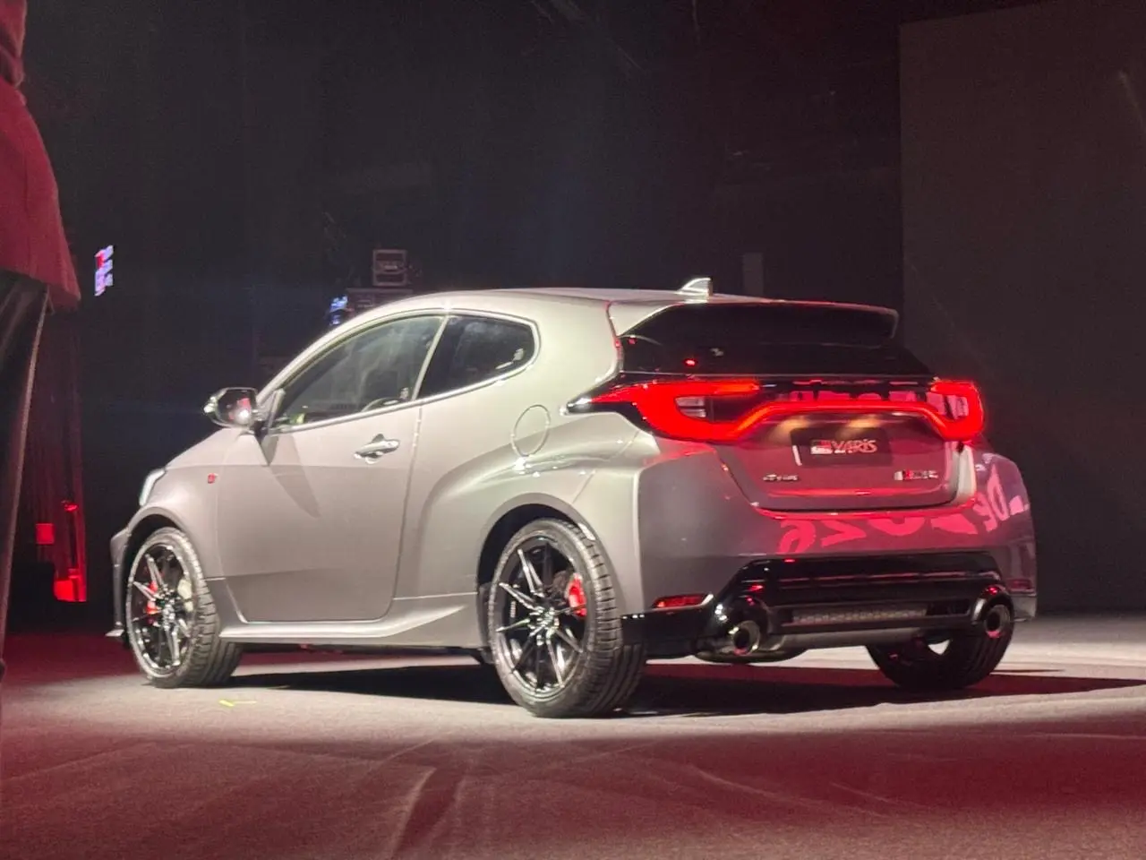 Toyota GR Yaris cinza visto de trás e com lanternas acesas