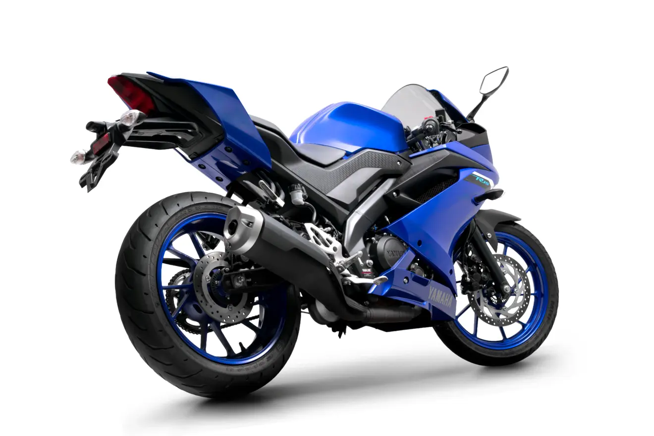 Motocicleta Yamaha R15 azul parada de traseira com fundo neutro